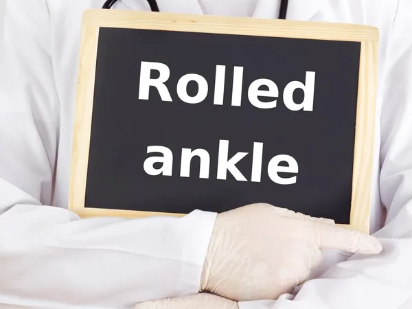 Doctor shows information on blackboard: rolled ankle — Stock Photo, Image