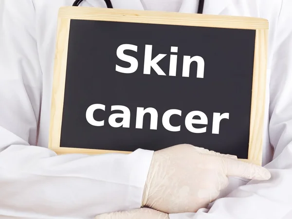Doctor shows information on blackboard: skin cancer — Stock Photo, Image