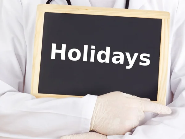 Doctor shows information on blackboard: holidays — Stock Photo, Image