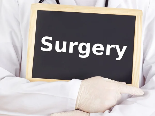 Doctor shows information on blackboard: surgery — Stock Photo, Image