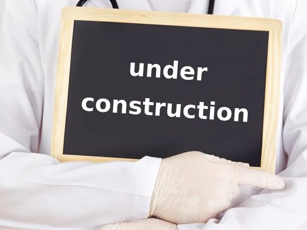 Doctor shows information: under construction — Stock Photo, Image