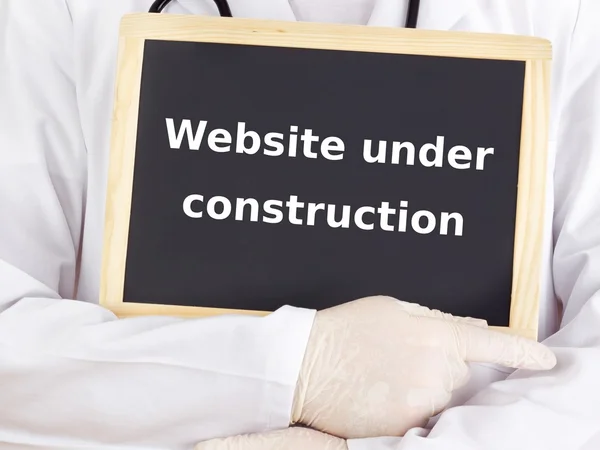Doctor shows information: website under construction — Stock Photo, Image