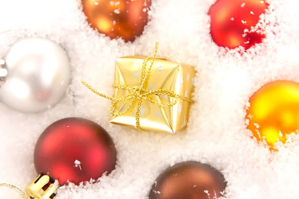 Weihnachtsbaumkugeln und Geschenk im Schnee — Stockfoto