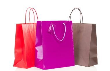 Beyaz masa üzerinde üç renkli alışveriş torbaları