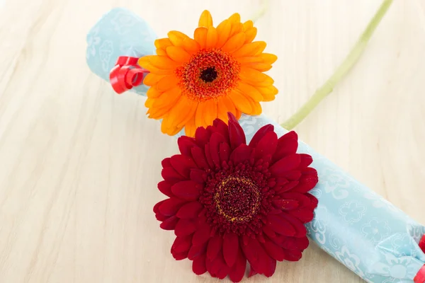 Two beautiful and colorful gerberas with blue gift — Stock Photo, Image