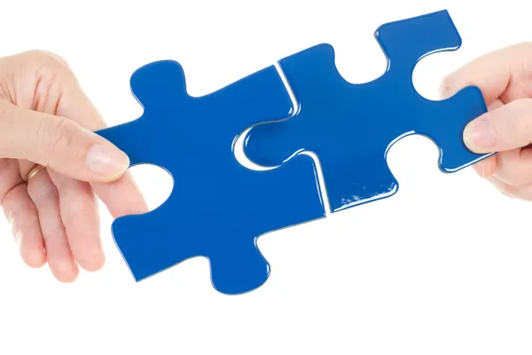 People putting two pieces of jigsaw together — Stock Photo, Image