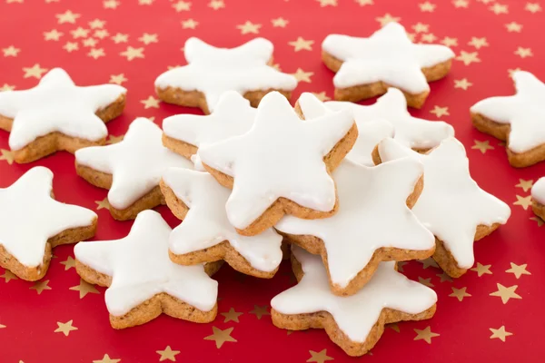 Biscoitos de canela em forma de estrela em fundo vermelho com estrelas douradas — Fotografia de Stock