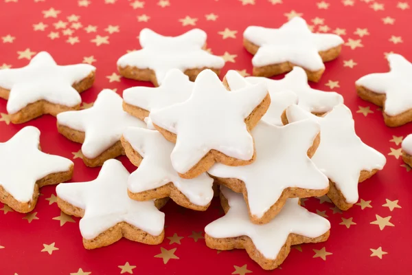 Galletas de canela en forma de estrella sobre fondo rojo con estrellas doradas —  Fotos de Stock