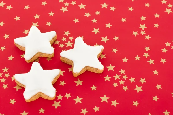 Ster vormig kaneel koekjes op rode achtergrond met gouden sterren — Stockfoto