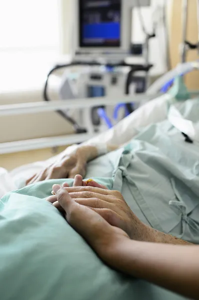 Uma jovem mão toca e segura uma velha mão enrugada no hospital — Fotografia de Stock