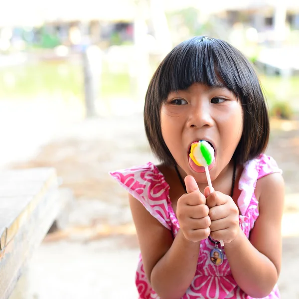 Cute little girl eating a lollipop in summertime — Stock Photo, Image