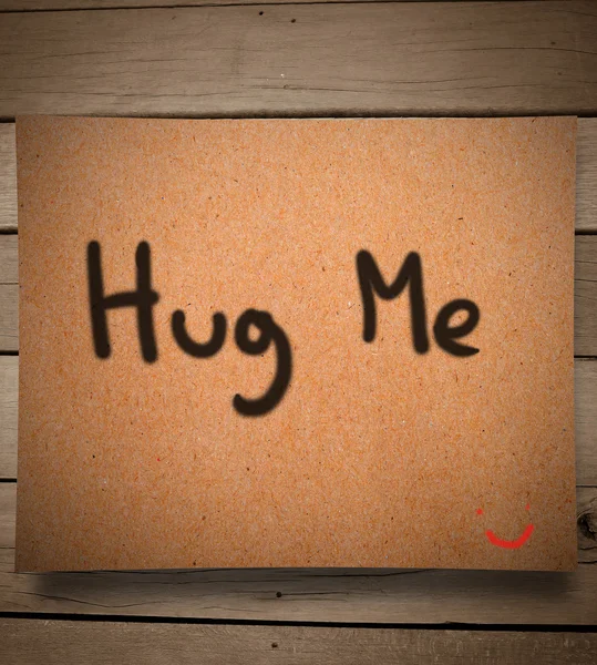 Hug me message on paper and wooden wall — Stock Photo, Image