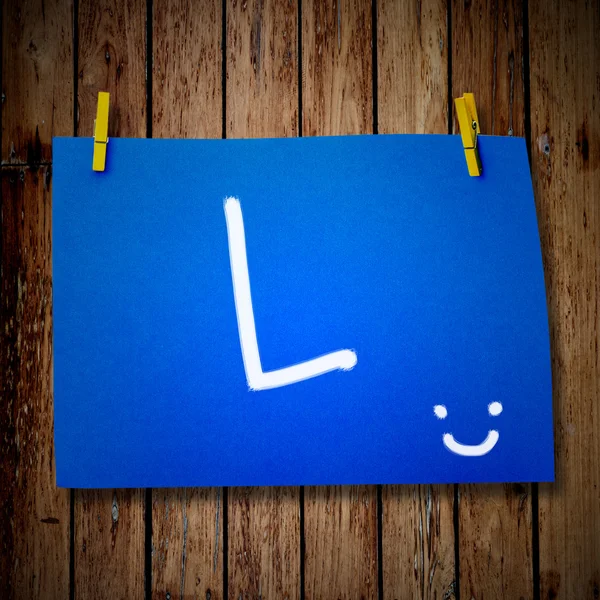 note paper and clothes peg on a wooden background with alphabet