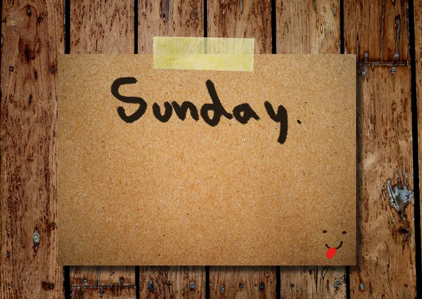 Sunday on note paper with wooden background — Stock Photo, Image