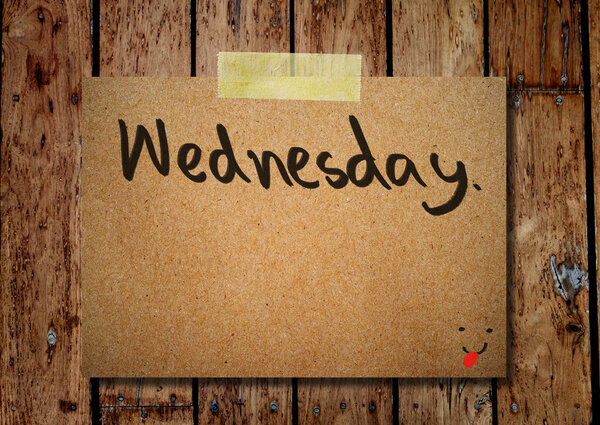 Wednesday on note paper with wooden background
