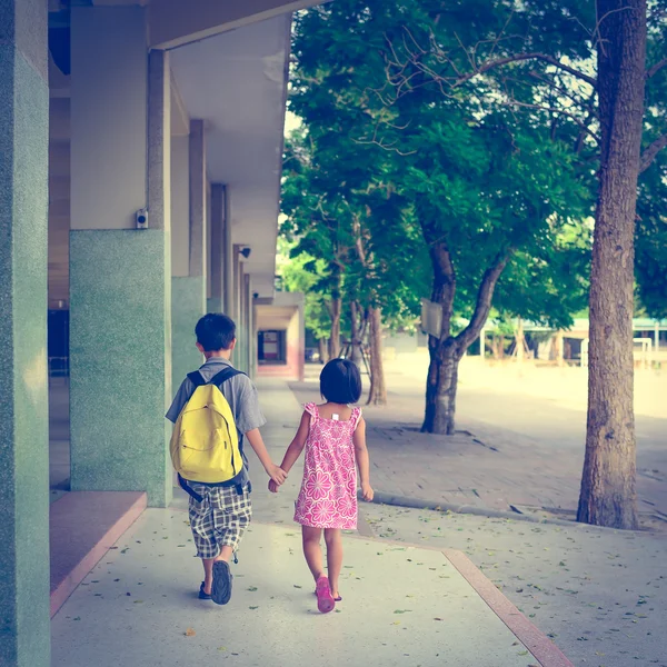 Menino e menina andando na escola com segurando as mãos em v — Fotografia de Stock