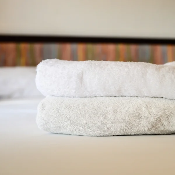 Ułożone spa białe ręczniki na łóżku — Zdjęcie stockowe