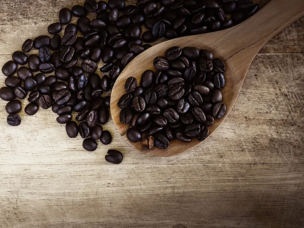 Chicchi di caffè su un mestolo di legno con sfondo in legno — Foto Stock