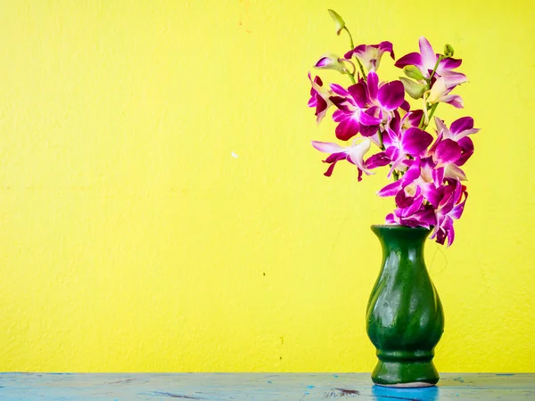 Orquídea púrpura y florero viejo verde con pared amarilla grunge — Foto de Stock