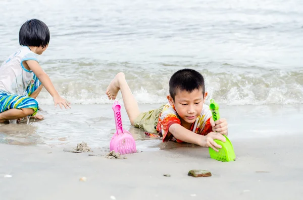 Thai brother and sister ages 6 and 4 have fun digging in the san — Stock Photo, Image