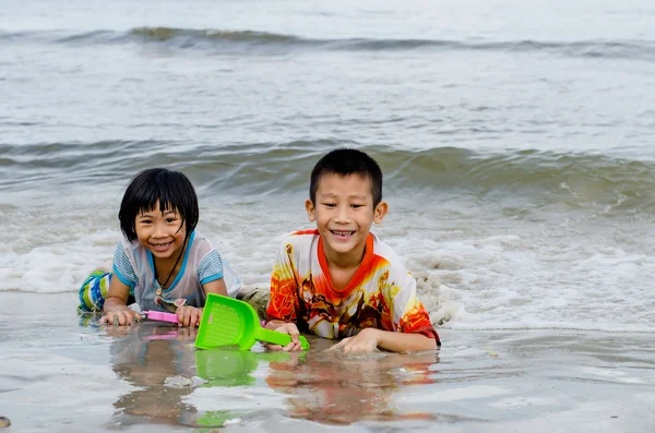 Thai brother and sister ages 6 and 4 have fun digging in the san — Stock Photo, Image