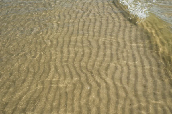 Отражение солнца в воде на песчаном берегу моря — стоковое фото