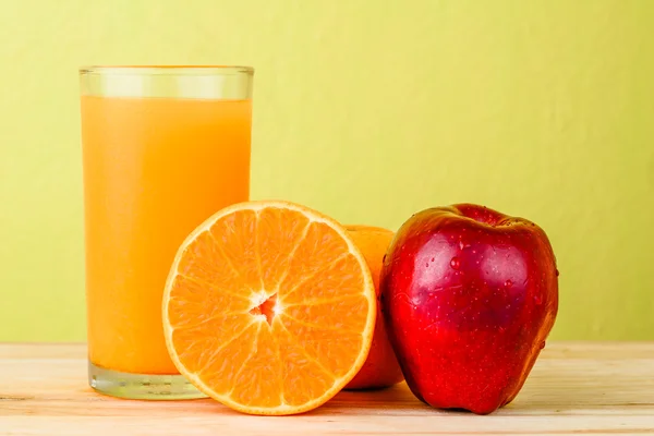 Apfel und Orange auf Holztisch vor gelbem Hintergrund — Stockfoto