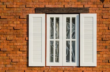güneşli bir günde kahverengi ahşap pencere üzerinde tuğla duvar