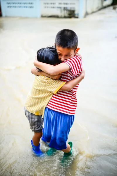 Brother and sister in blue boots holding togetherin flood disast — Stock Photo, Image