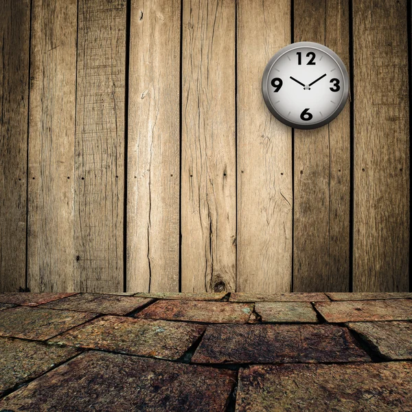 Old clock on grungy wooden wall and brick floor — Stock Photo, Image