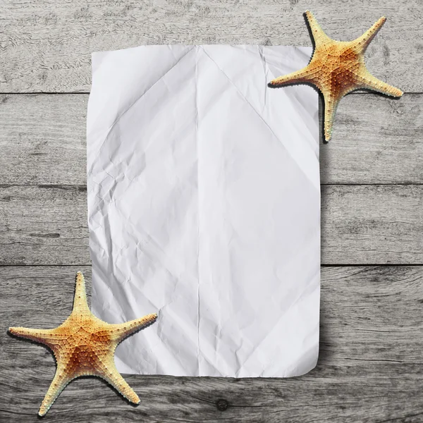 Papel arrugado en blanco sobre fondo de madera con estrellas de mar. Vacaciones — Foto de Stock