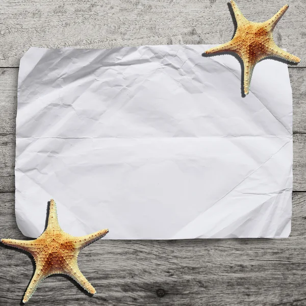 Carta bianca sgualcita su fondo di legno con stelle marine. — Foto Stock
