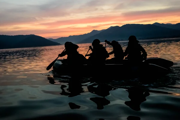 Silhouette de soldats ramant bateau en caoutchouc sur le lac — Photo