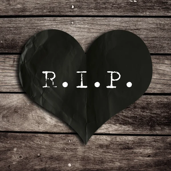 R.I.P. word on black heart shape with wooden wall, broken heart c — стоковое фото