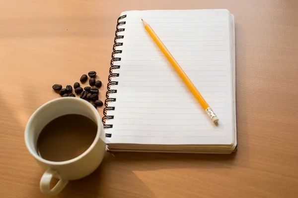 Copo de café notebook em branco no fundo de madeira — Fotografia de Stock