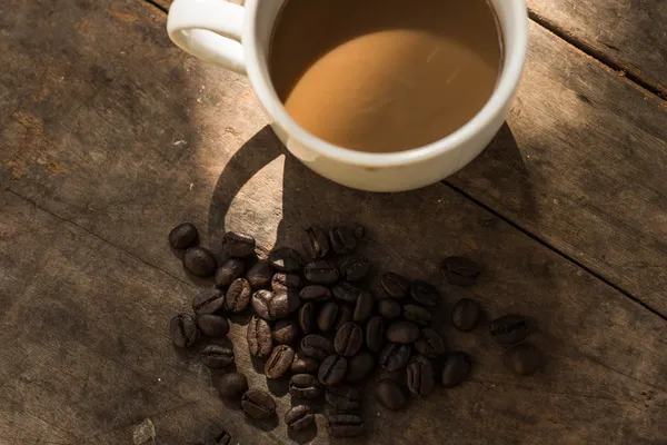 Tasse Kaffee und Kaffeebohnen auf Holz Hintergrund mit Natur l — Stockfoto