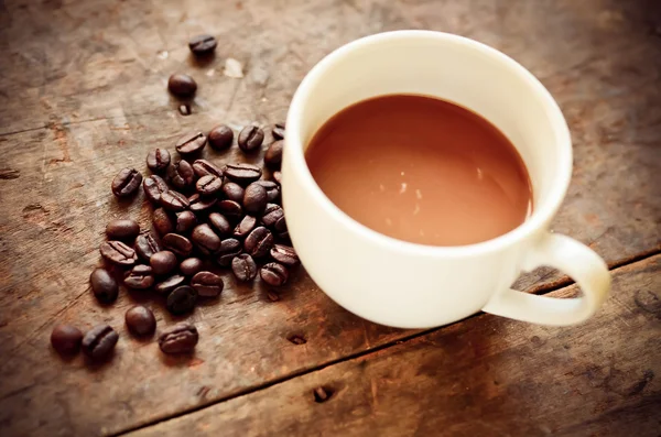杯のコーヒーとコーヒー豆自然 l で木製の背景に — ストック写真