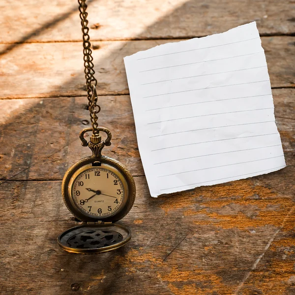 Vintage pocket watch on chain and torn paper on wooden backgroun — Stock Photo, Image