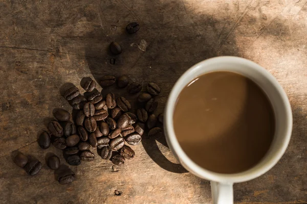 Tasse Kaffee und Kaffeebohnen auf Holz Hintergrund mit Natur l — Stockfoto