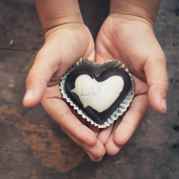 Любовная записка на черно-белом шоколаде в руке ребенка — стоковое фото