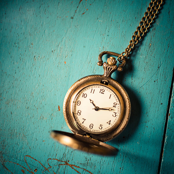 Old style pocket watch on blue wooden background