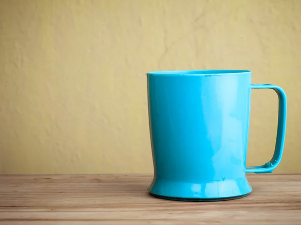 Taza sobre mesa de madera sobre pared azul — Foto de Stock