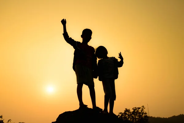 Boy and girl are climbing the hill during sun set. — Stock Photo, Image