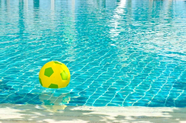Pelota de goma verde y amarilla flotando en la piscina —  Fotos de Stock