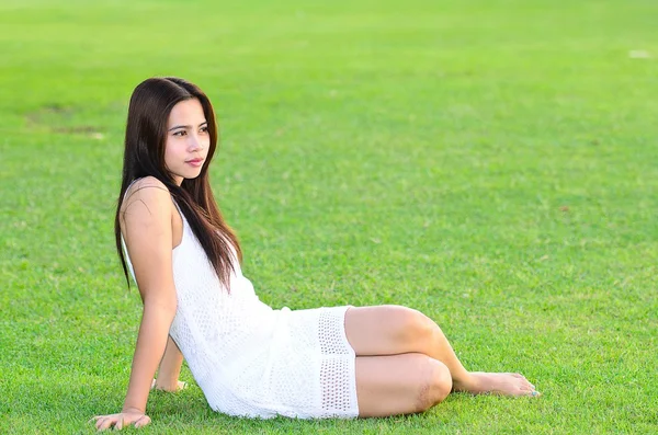 Yeşil çimenlerin üzerinde oturan güzel sağlıklı genç kadın — Stok fotoğraf