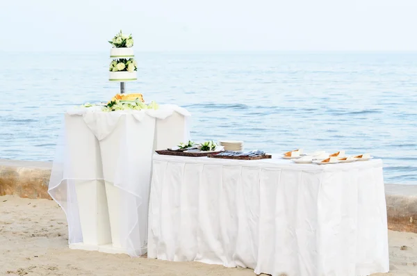 Vit bröllopstårta på bord på stranden. — Stockfoto