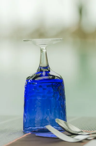 Modré sklo na stůl nastavení protilehlých s výhledem na bazén — Stock fotografie