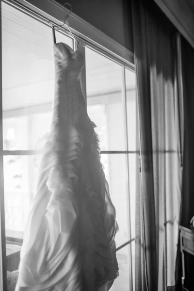 Black and White of a wedding dress hanging up by the window. — Stock Photo, Image