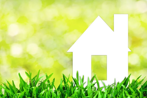Белый бумажный дом и весенняя зеленая трава с зеленым боке — стоковое фото