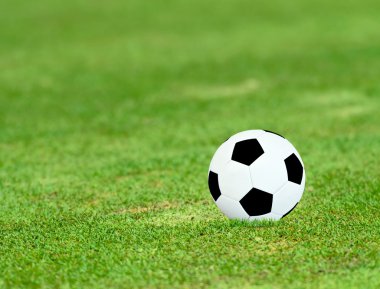 güneşli gün ile yeşil sahada futbol topu.